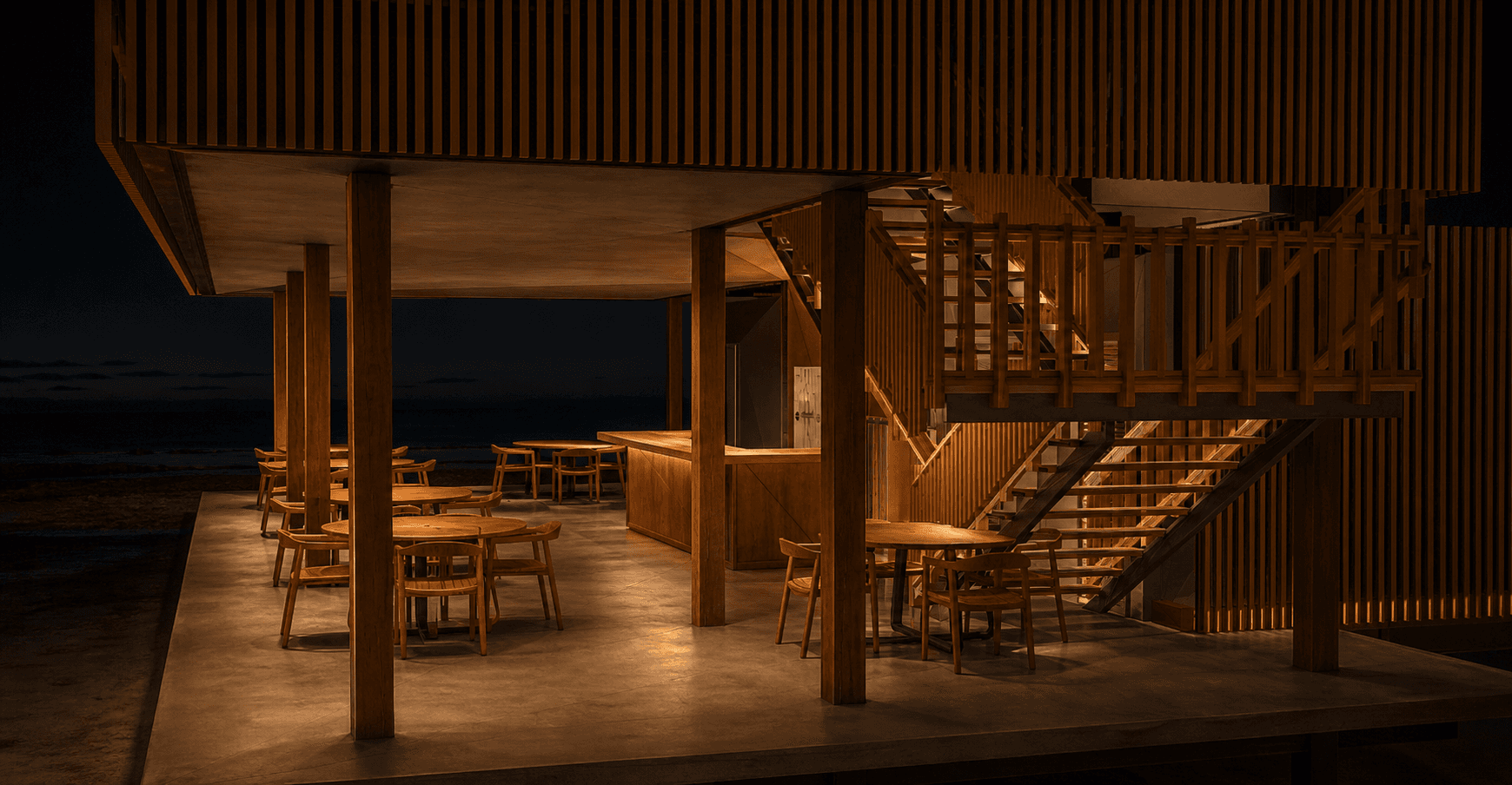 Rez-de-chaussée du Beach Club avec tables en bois et escalier éclairé