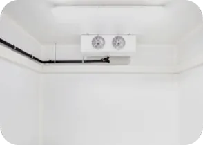 Photographie réelle de l'intérieur d'une chambre froide avec évaporateur et réseau de condensats